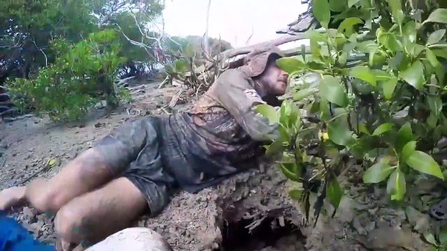 Un homme disparaît dans un trou boueux et ressort avec un gigantesque crabe