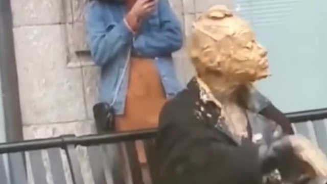 Une femme se recouvre le visage avec du beurre de cacahuète en pleine rue