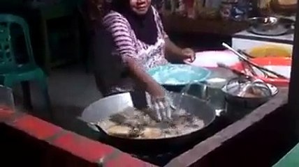 Une thaïlandaise  plonge ses mains dans l'huile bouillante