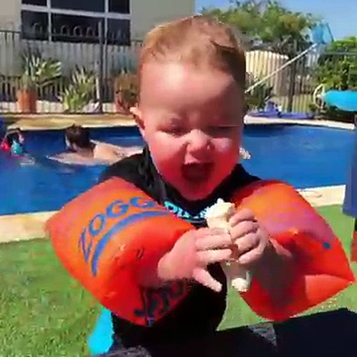 Un enfant veut manger une banane avec des brassards de natation