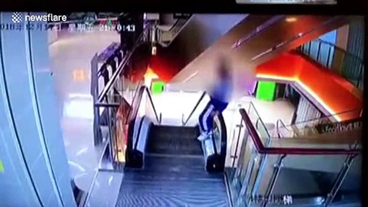 Naughty student climbs onto escalator handrail and falls one storey