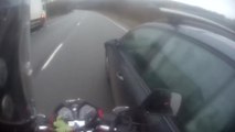 Une voiture double et tape dans une moto en la doublant dans sa voie