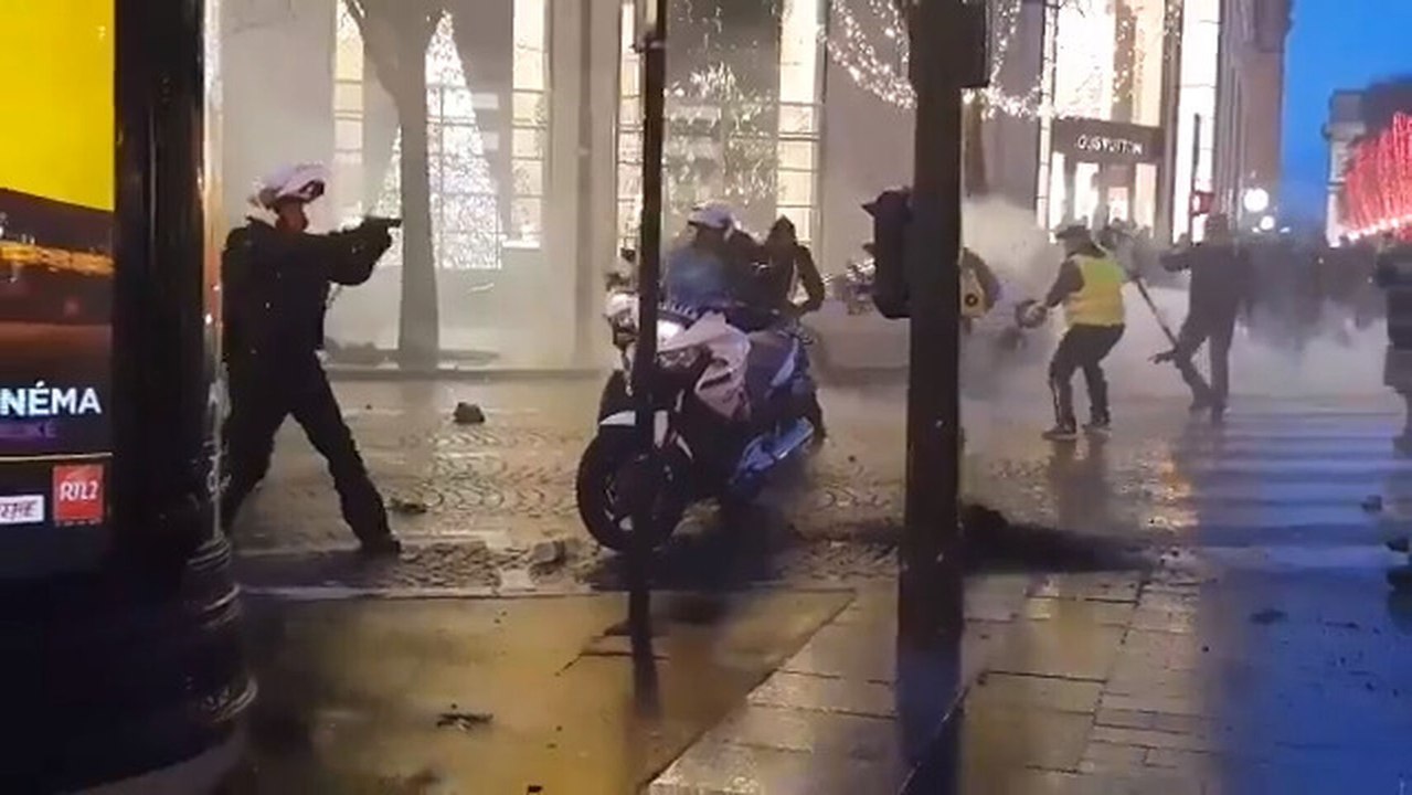 Un policía saca su arma en una protesta de los...