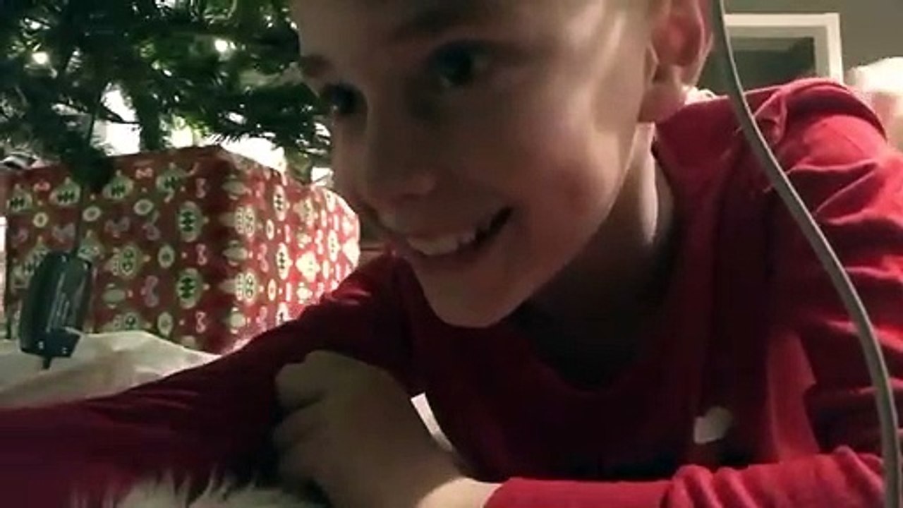 Un enfant place une caméra sous le sapin pour filmer le Père Noël