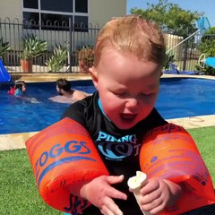 Baby attempts to eat banana while wearing floaties