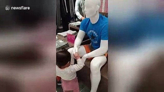 Adorable moment polite toddler greets mannequins inside shopping mall