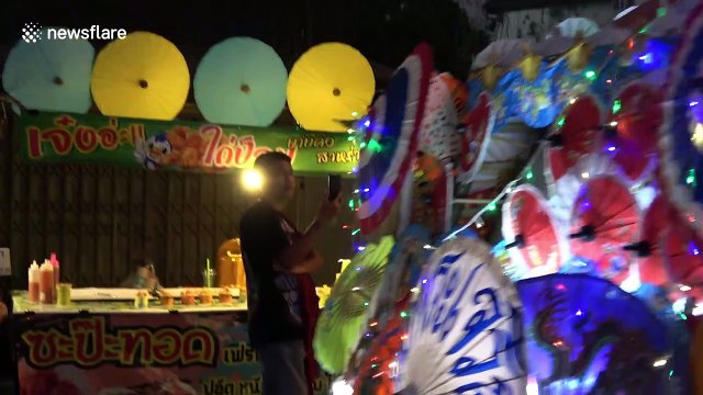 Thai locals wear traditional dress for evening parade at umbrella festival