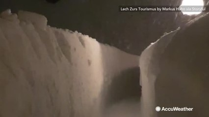 With roads impassable, ski resort guests travel between towering walls of snow