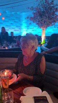 80 ans : mamie danse sur la table avec son gâteau d'anniversaire à la main