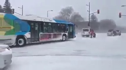 Une chaîne de 4x4 tente de tracter un bus bloqué par la neige.