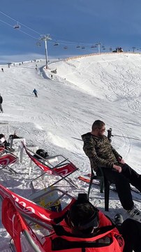 Backflip en ski au-dessus des touristes dans les transats sur la piste de ski