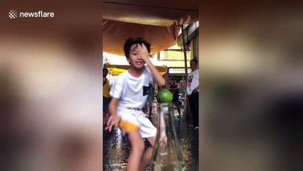 Dizzy kids try to flick lime from bottle top in amusing party game