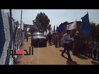 الدستور | تلاميذ قرية البساتين ببنى سويف يستقبلون محلب والعصار بالأعلام