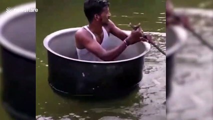 Man rows over water in cooking pot boat with spatula paddle