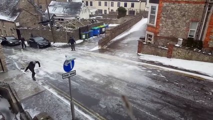Un groupe d'hommes essayent en tout moyen de monter une route glissante