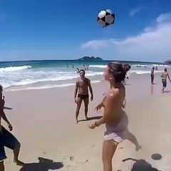Près de la mer, beau meteo, et le chien joue au football avec les gens.
