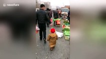Smart dad uses strawberry to encourage son to follow him through market