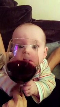 Bébé déjà accro au vin ? Il essaye de le boire à travers le verre lol