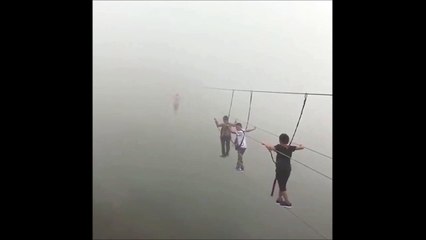 Ces touristes traversent un pont suspendu perdu dans la brume... Impressionnant
