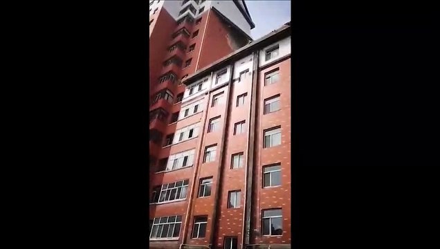 La façade d'un immeuble se détache à cause du vent et chute sous les yeux des passants
