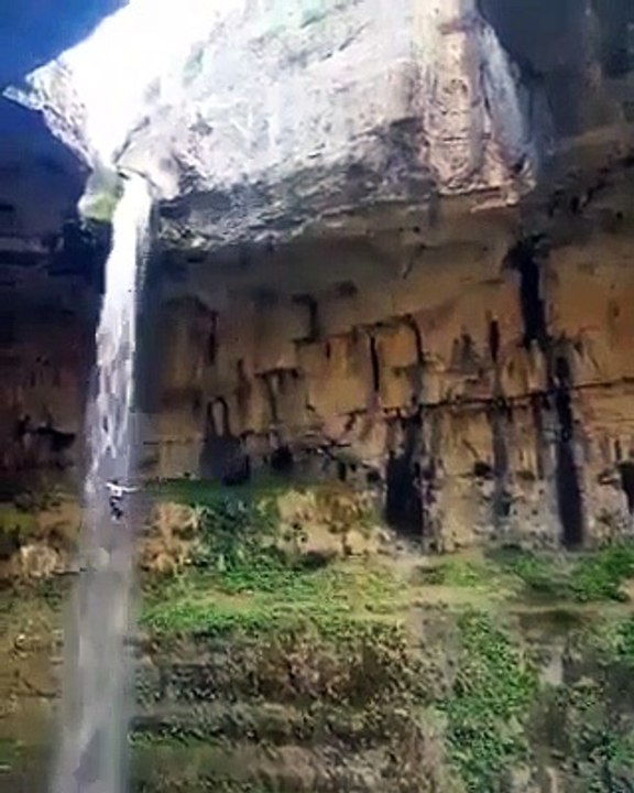 Cet homme plonge du haut de cette falaise le long d'une chute d'eau magnifique... vertigineux