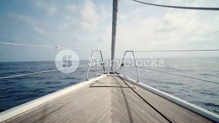 Front view on luxury sailing yacht boat nose with wooden parquet floor, swaying in open sea at sunny day. Relaxing and peaceful background holiday shot