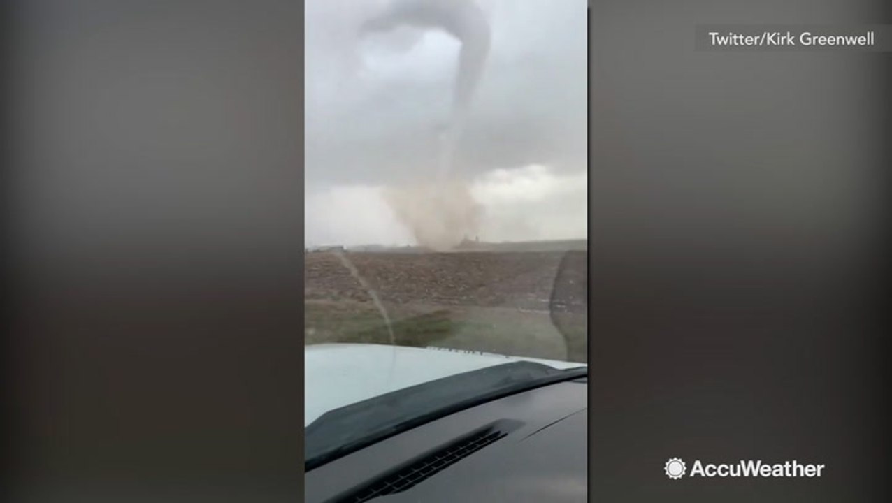 Large tornado towers over driver passing by