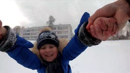 Un papa fait tourner son enfant dans la neige