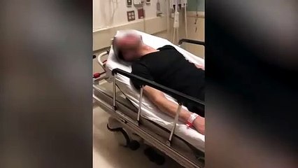 Un policier frappe un homme sur un lit d'hôpital