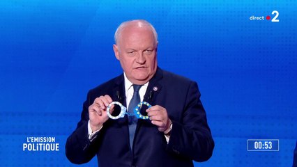 Premier à parler, François Asselineau présente une paire de menottes aux couleurs du drapeau européen