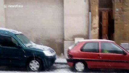 Unseasonal hailstorm pummels cars parked on a street in Barcelona