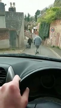 Une femme en béquilles marche au milieu de la route et l'empêche de passer !