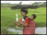 Woman spinning while on the go, with child on back, wood pile on head!