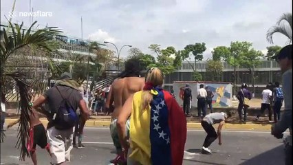 Protesters in Caracas throw stones at the National Guard motorcycle