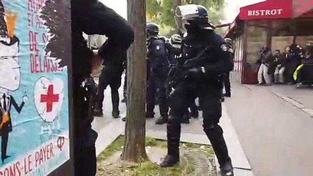 Un policier renvoie un pavé sur des manifestants (1er mai 2019)