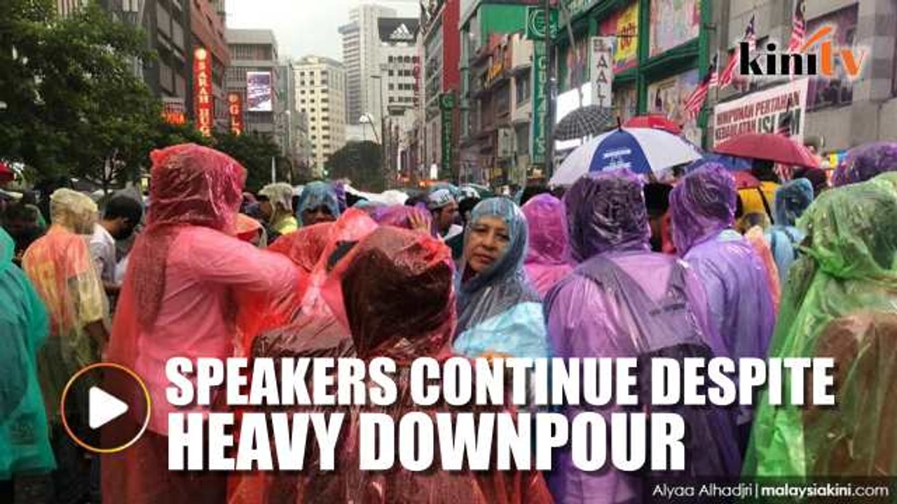 Speakers continue  with their speehes at rally despite heavy downpour