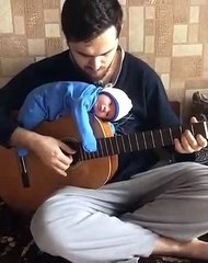 Il joue avec son bébé posé sur la guitare