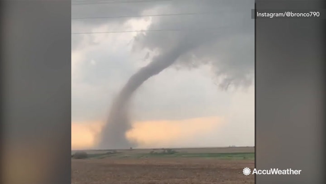 Large tornado swirls over open field