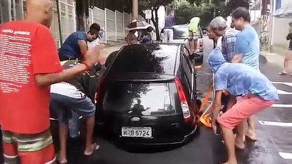 Um grupo de pessoas tiram um carro de uma cratera