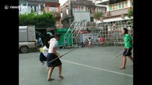 Thai students practice sword fighting during break time