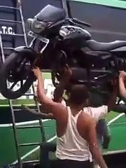 Il met sa moto sur la tête pour la charger sur le toit du bus... Costaud