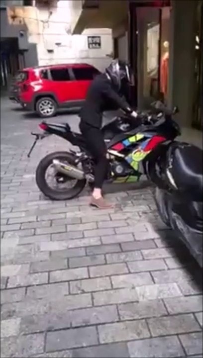 Ce motard tente un gros burn devant une vitrine...