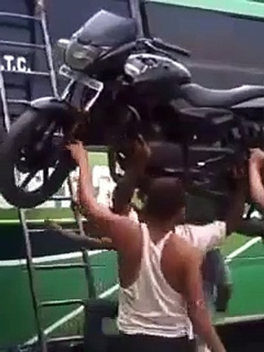 Il met sa moto sur la tête pour la charger sur le toit du bus. Costaud