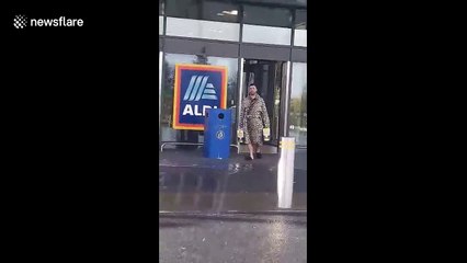 Funny moment man in leopard print gown walks out of Aldi with crate of beer