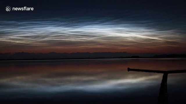 Shiny noctilucent clouds 'dance' in the skies above lake in the Netherlands