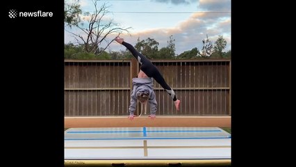 Daughter supports her dad as he attempts to cartwheel on a balance beam in Australia