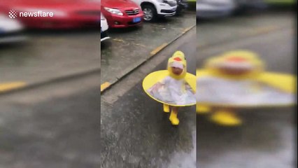 Baby girl in a duck themed coat joyfully runs through the rain in Shanghai