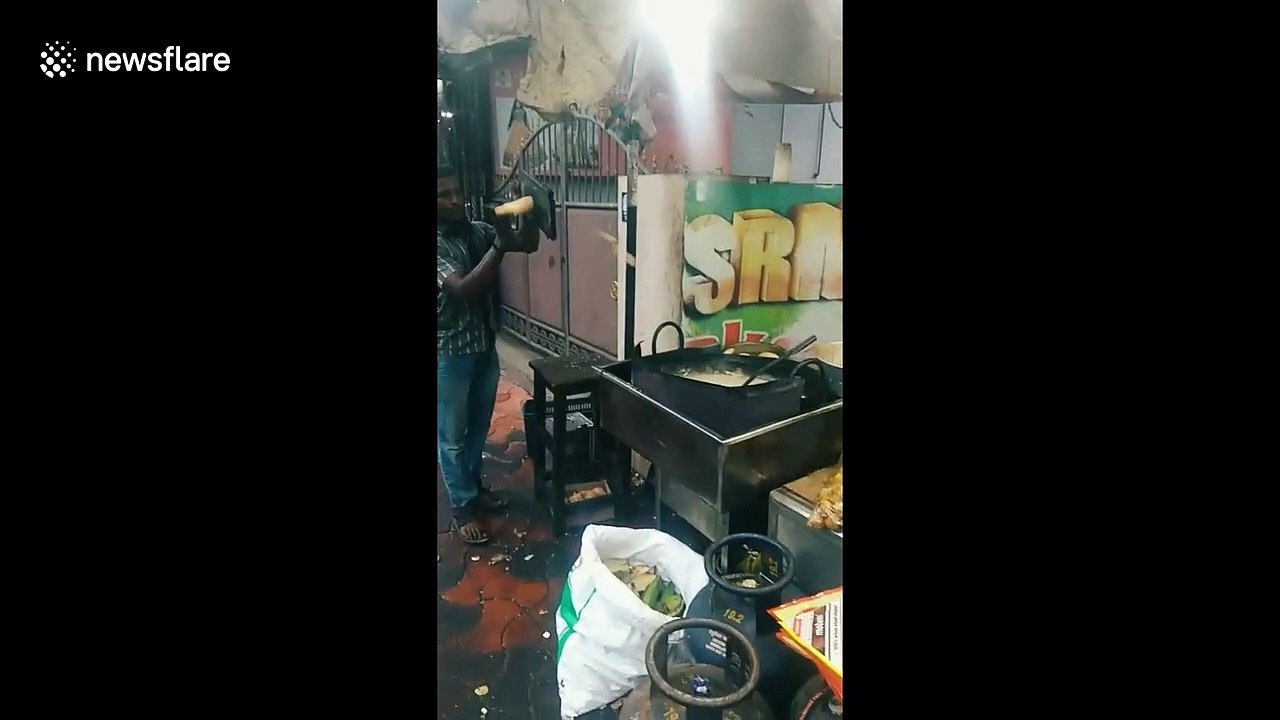 Chef in India lands potato slices into frying pan while standing a few feet away