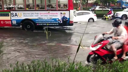 Motorists drive through flood waters during morning rush hour in Bangkok