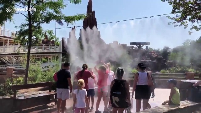 Families visiting Disneyland Paris cool down under water mist during European heatwave